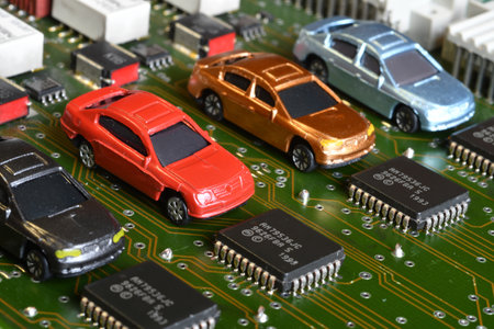 Toy cars on electronic board and microchip. The shortage of microchips and semiconductors creates a...