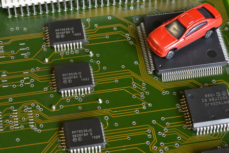 Toy cars on electronic board and microchip. The shortage of microchips and semiconductors creates a...