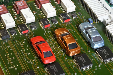 Toy cars on electronic board and microchip. The shortage of microchips and semiconductors creates a...