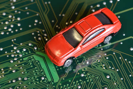 Toy cars on an electronic board with integrated circuits. The shortage of microchips and semiconductors creates a shortage of new cars. Conceptual image for semiconductor shortage disrupting production of the automotive industry.の写真素材