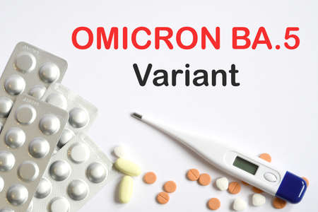 Medicinal pills, tablets with fever thermometer and text "OMICRON BA.5 Variant" on white background.の写真素材