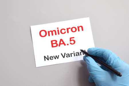 Covid-19 new variants of Omicron. Doctor's hand in blue glove with marker and writing "Omicron BA.5 New Variant" on white paper. Concept for the new variants Covid 19 Omicronの写真素材