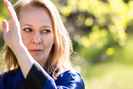 Woman doing tai Chi exercises in a green Park on a Sunny day close up