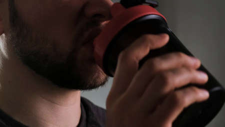 Close-up of a bearded athletic man drinking a sports supplement from a shakerの写真素材