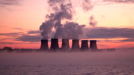 Smoke escapes from the steam pipes of a nuclear power plant against a dramatic red sky. Timelapse