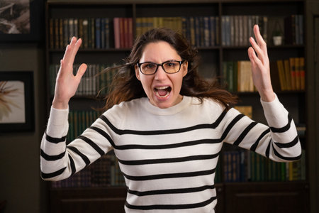 Portrait of an angry woman boss with glasses in the office looks at the camera and screamsの写真素材
