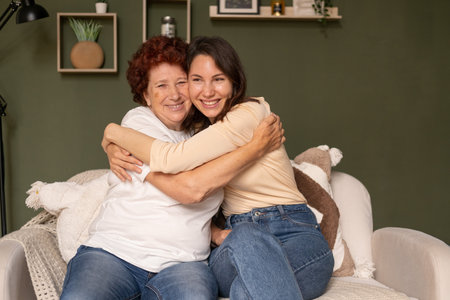 Portrait of a modern happy grandmother and granddaughter sitting in the living room during the day...