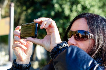 Dark Haired Mature Woman Taking  A Picture With Cellphone