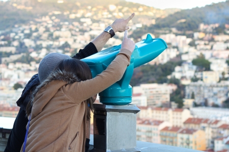 Boy and Girl looking through a turquoise telescope and pointing somewhereの写真素材