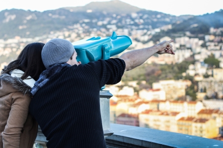 Boy and Girl looking through a turquoise telescope and pointing somewhereの写真素材