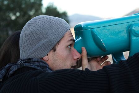 Boy looking through a turquoise telescopeの写真素材