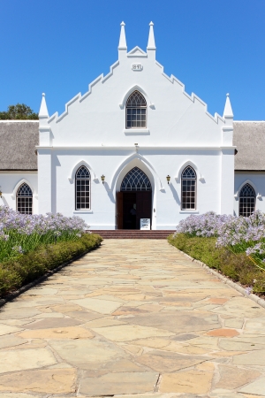 White Church in Franschhoek in front of blue sky with stone pathwayの写真素材