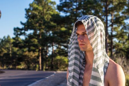 Male model outdoors with scarf on his head looking seriously