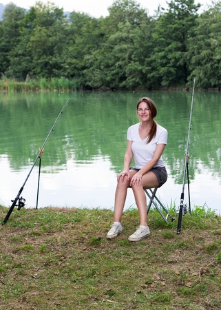 Brunette Woman Fishing at a lake with green waterの写真素材