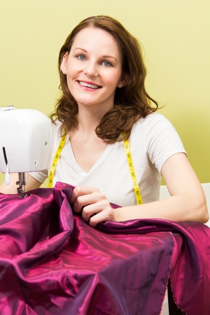 Brunette european woman sewing diy at home in front of yoellow backgroundの写真素材