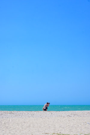 A couple kisses on a deserted beach facing the sea.の写真素材