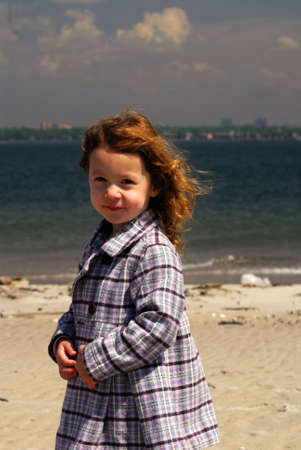 A little girl posing on a sunny beach.の写真素材