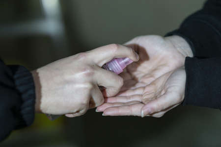 shop assistant disinfecting the client's hands with alcoholの写真素材