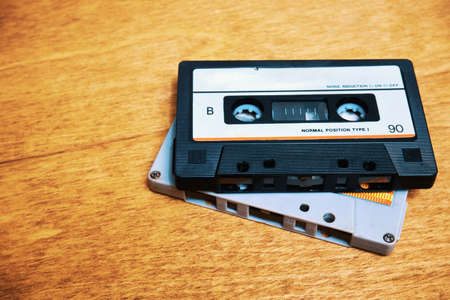 Two vintage audio cassettes lie on the wooden tableの写真素材