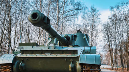 The barrel of a cannon of a Russian self-propelled howitzer against the background of trees and the...