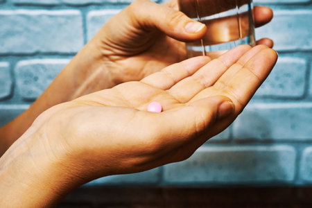 Female hands with pill and glass of water