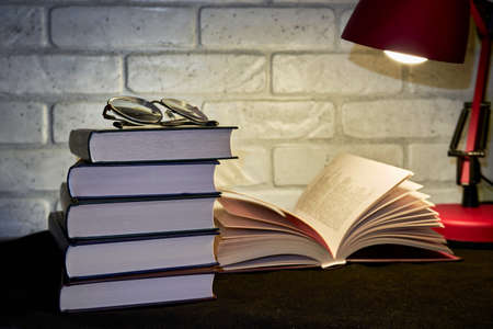 Books, glasses and an electric table lamp
