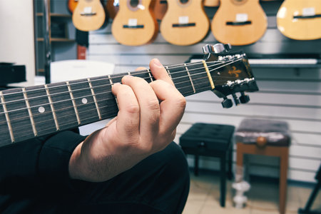 Ryazan, Russia - October 9, 2022: Musician playing guitar in a guitar shop. Buying a guitar from a...