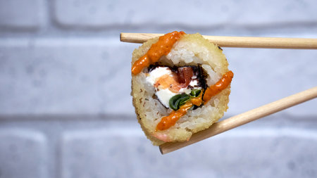 Sushi roll with chopsticks on brick wall backgroundの写真素材