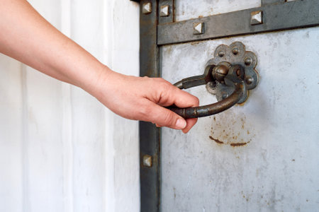A woman's hand opens an ancient door. Door handle in the form of a ring