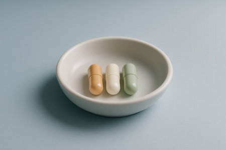 Pastel Capsules Arranged In Minimal Ceramic Bowl On Blue Surfaceの素材