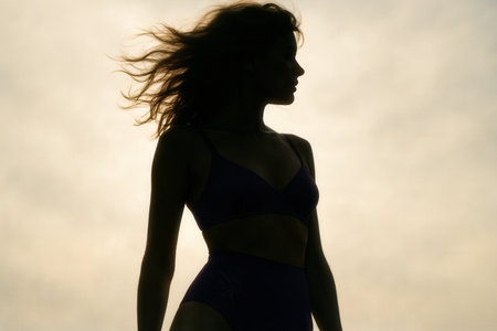 Silhouette Of Woman In Swimwear Against Dramatic Evening Sky With Windblown Hairの素材