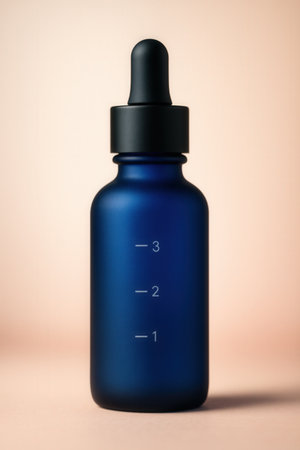 Minimal Cobalt Blue Dropper Bottle For Skincare Serum On Soft Peach Backgroundの素材