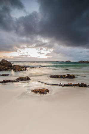 Long exposure photography of waves crashing over rocks at sunrise with storm clouds buildingの写真素材