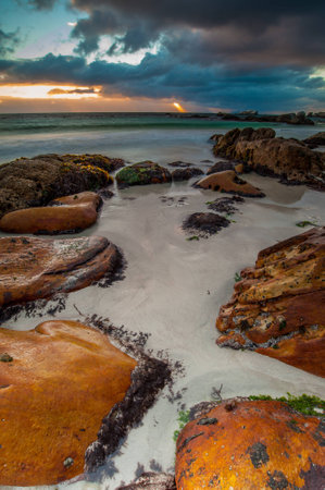 Long exposure photography of waves crashing over rocks at sunrise with storm clouds buildingの写真素材