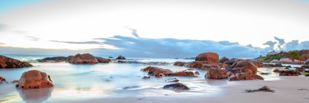 Long exposure photography of waves crashing over rocks at sunrise with storm clouds buildingの写真素材