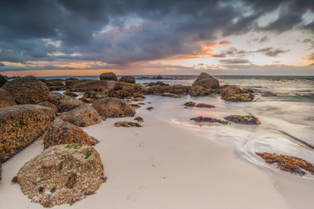 Long exposure photography of waves crashing over rocks at sunrise with storm clouds buildingの写真素材