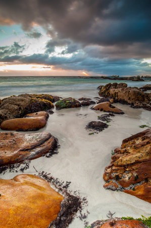Long exposure photography of waves crashing over rocks at sunrise with storm clouds buildingの写真素材