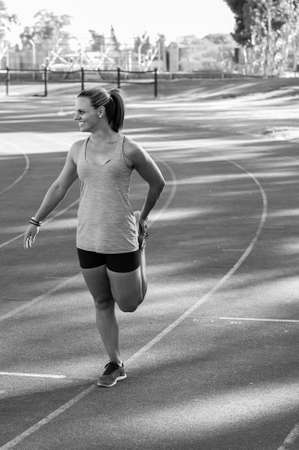 vibrant image of a female athlete stretching on a running trackの写真素材