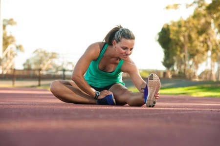 vibrant image of a female athlete stretching on a running trackの写真素材