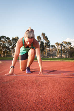 An athletic looking female runner on an outdoor track in summerの写真素材