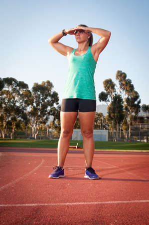 An athletic looking female runner on an outdoor track in summerの写真素材