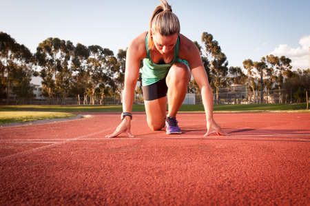 An athletic looking female runner on an outdoor track in summerの写真素材