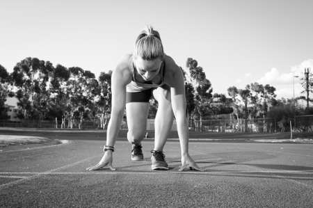 An athletic looking female runner on an outdoor track in summerの写真素材