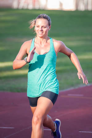 An athletic looking female runner on an outdoor track in summerの写真素材
