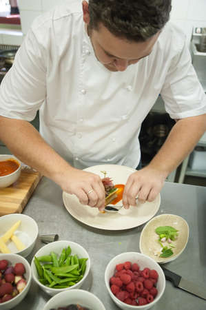 A chef prepares and plates food in a kitchenの写真素材