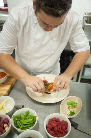 A chef prepares and plates food in a kitchenの写真素材