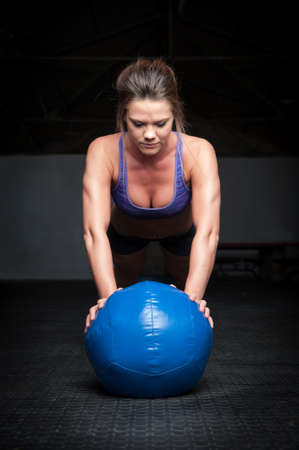 woman doing plank exercise on a ballの写真素材