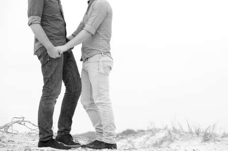 gay couple taking a walk along the beach holding handsの写真素材