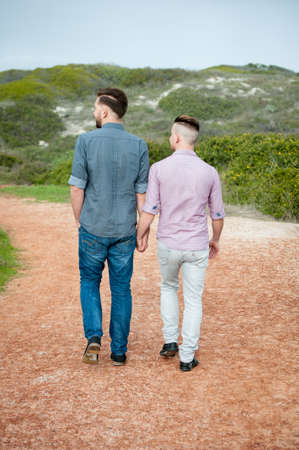 gay men walk down a gravel path while embracingの写真素材