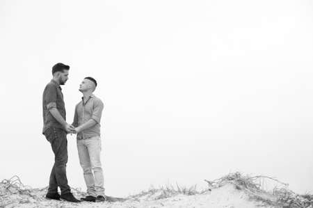 gay men lovingly embracing and cuddling on a beachの写真素材